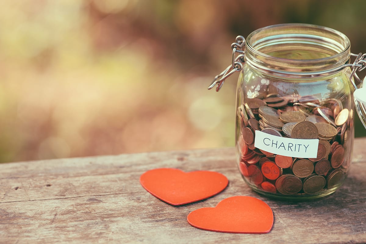 Money jar full of coins for charity and a couple of handcrafted wooden heart shapes. Shallow depth of field. Shot with Canon EOS 5D mark ii.