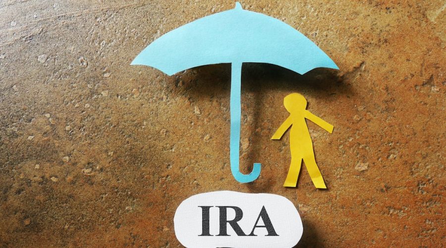 Paper cutout figure with an umbrella and IRA message - Individual Retirement Account concept