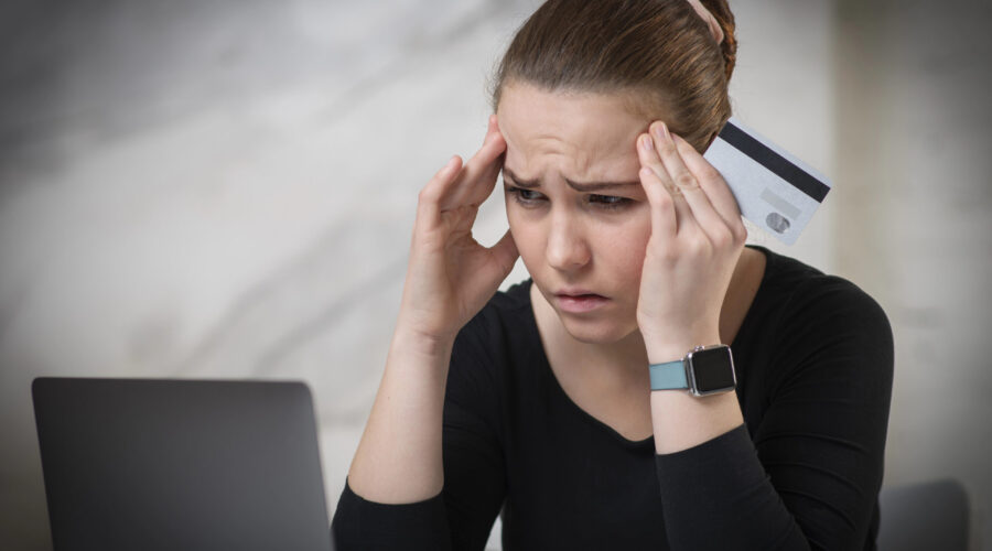 Woman looking at her laptop holding her forehead